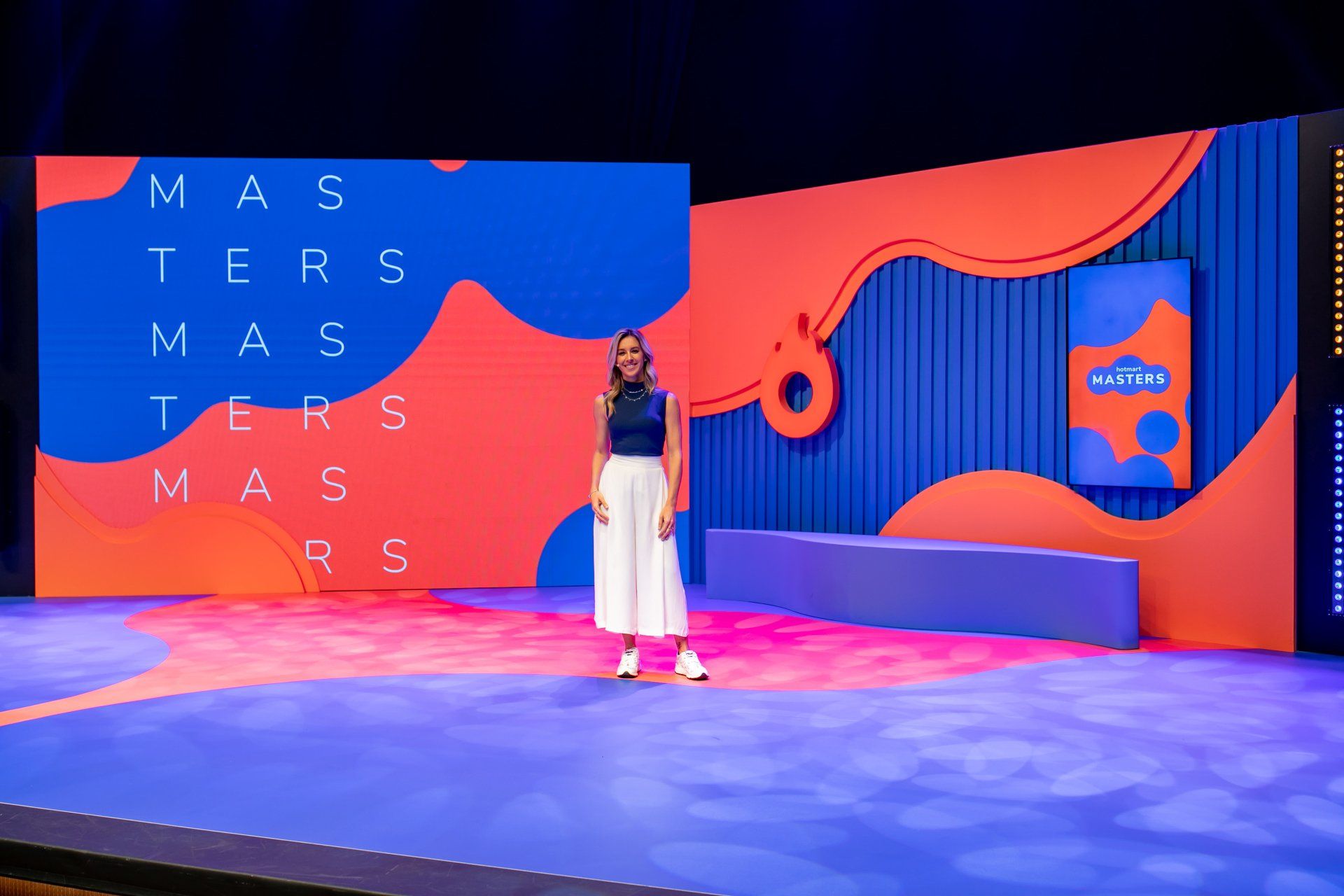 A woman is standing on a stage in front of a large screen.
