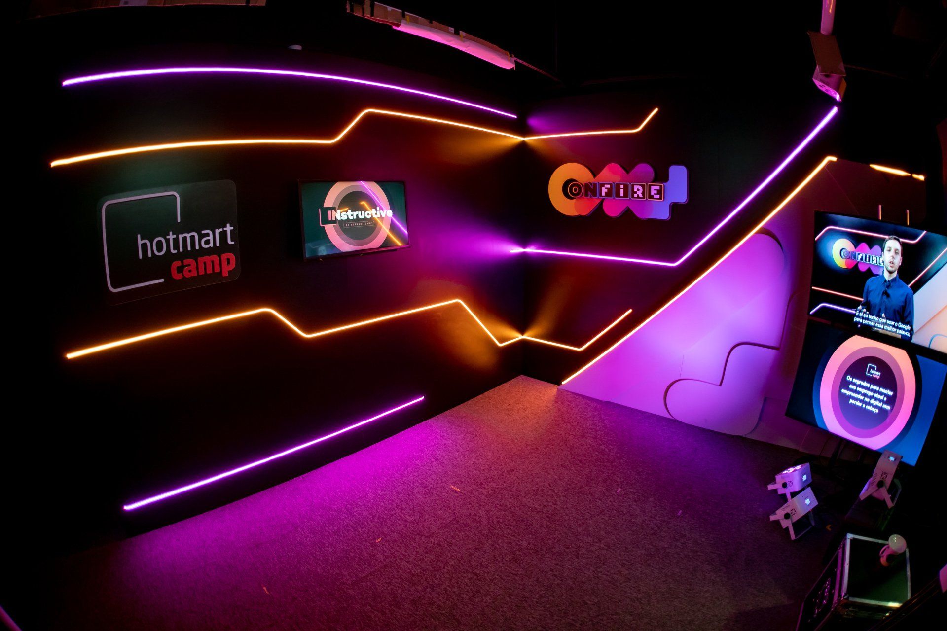 A room with a lot of neon lights and a sign that says hotmart camp