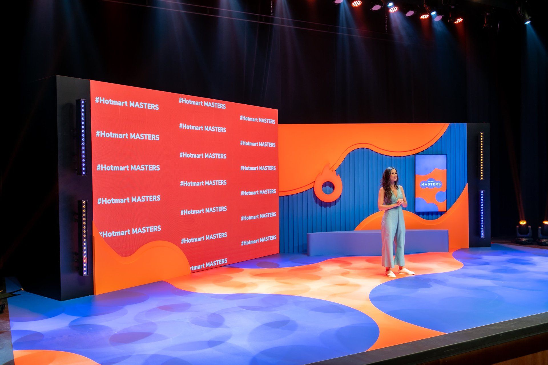 A woman is standing on a stage in front of a large screen.