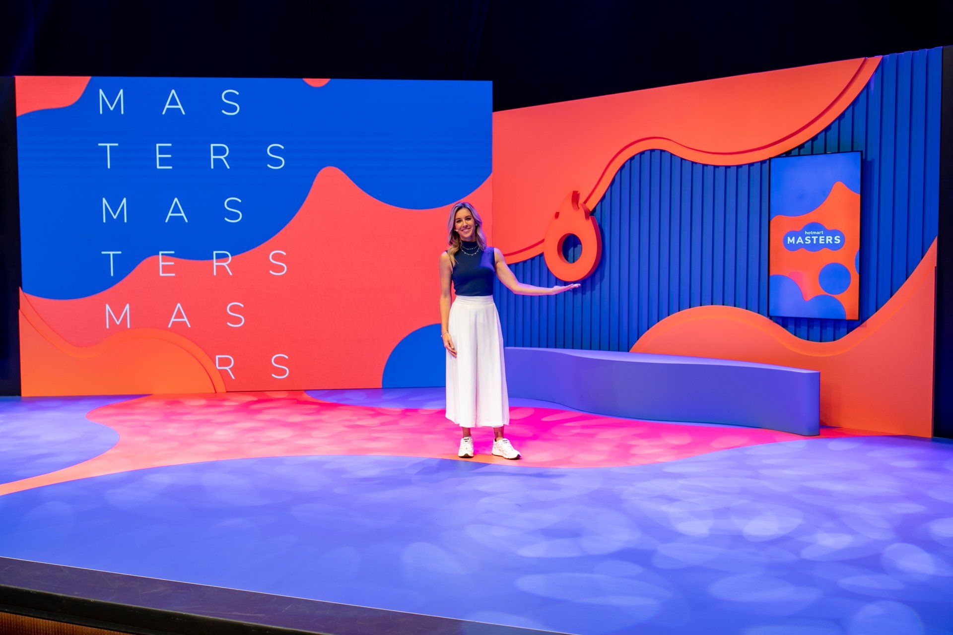 A woman is standing on a stage in front of a large screen.