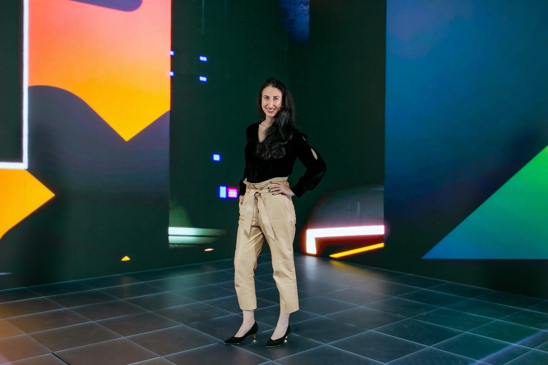 A woman is standing in front of a large screen in a dark room.