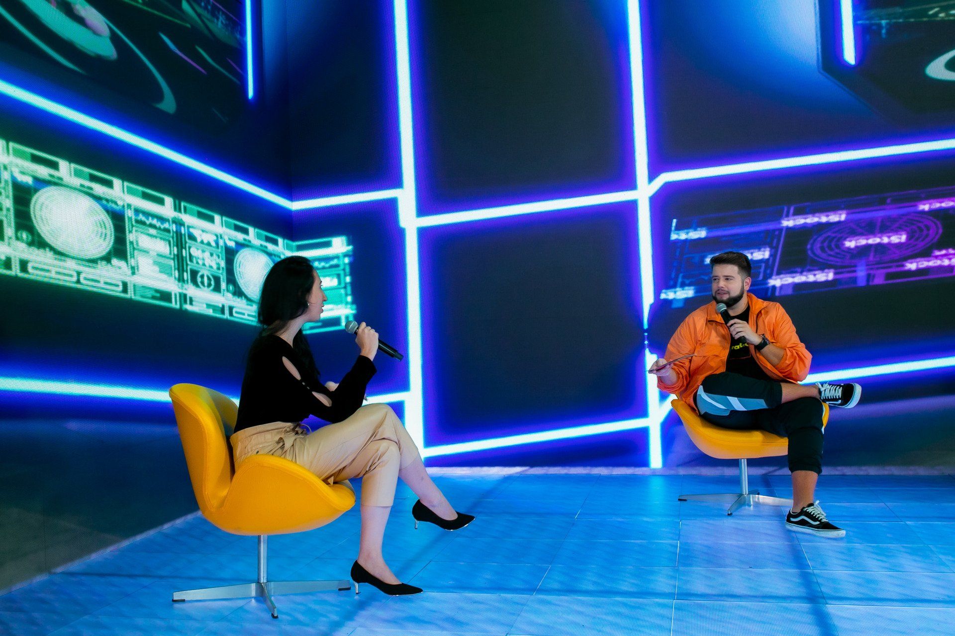 A man and a woman are sitting in chairs talking to each other.