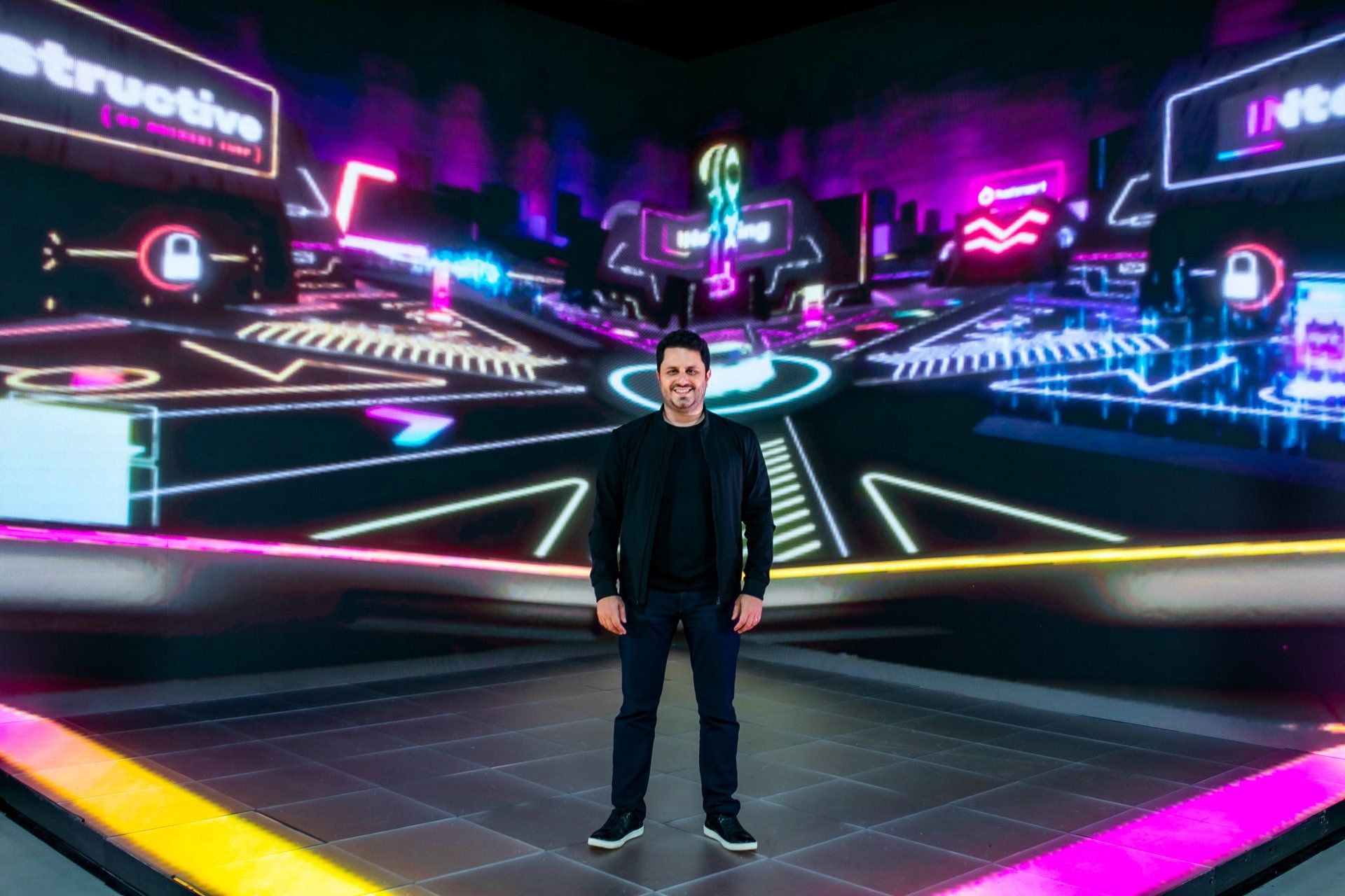 A man is standing in front of a large screen.