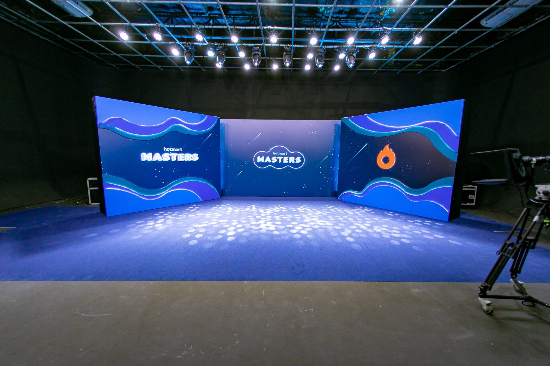 A large room with a blue carpet and a camera on the floor.
