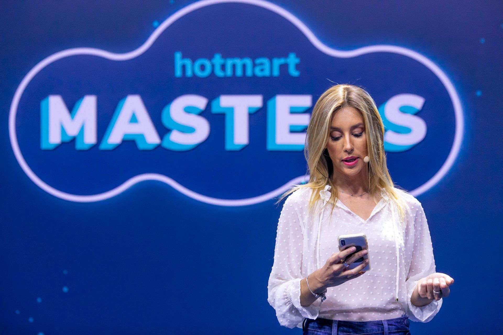 A woman is standing in front of a sign that says hotmart masters