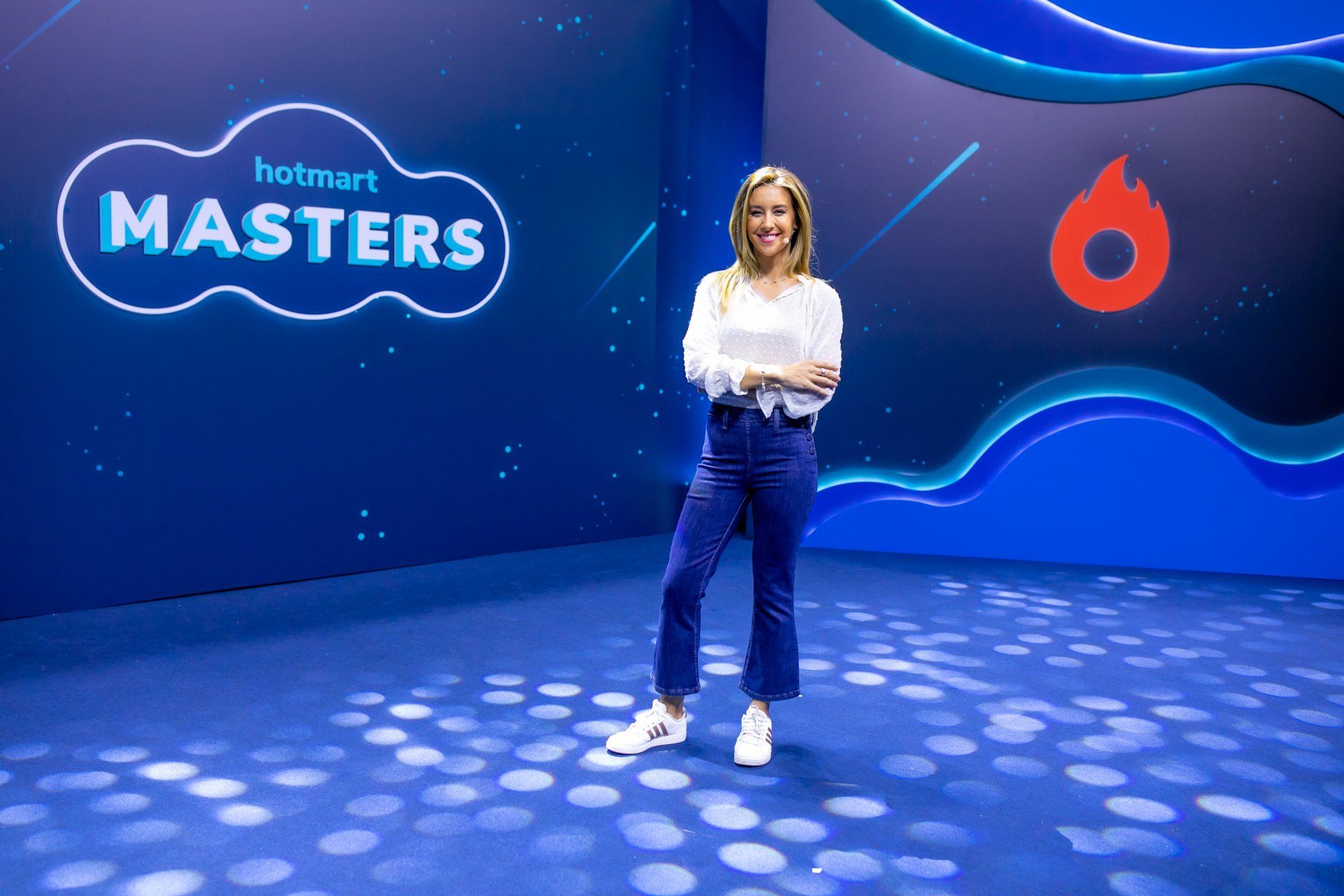 A woman is standing in front of a sign that says hotmart masters