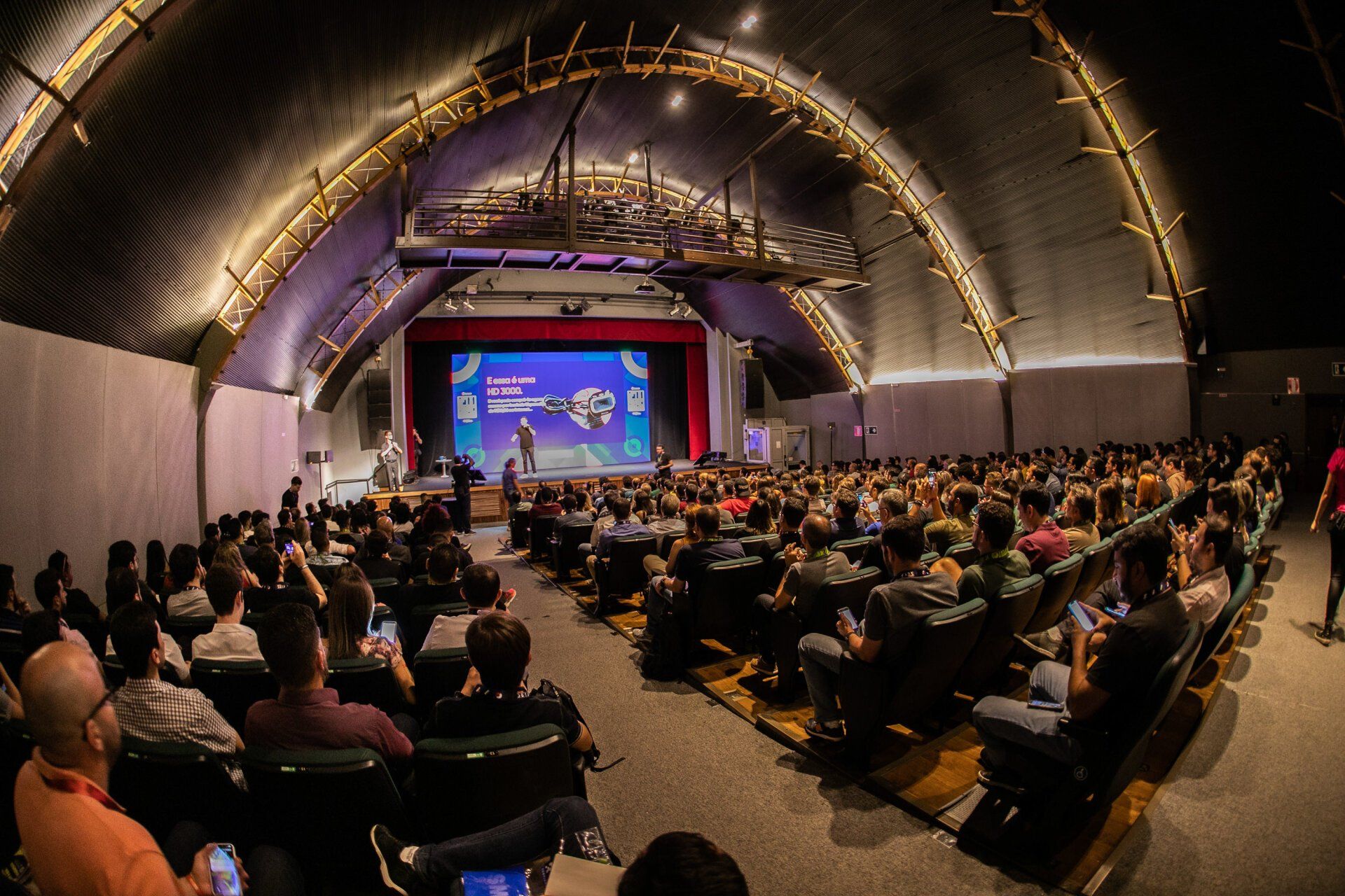 A large group of people are sitting in an auditorium watching a presentation.