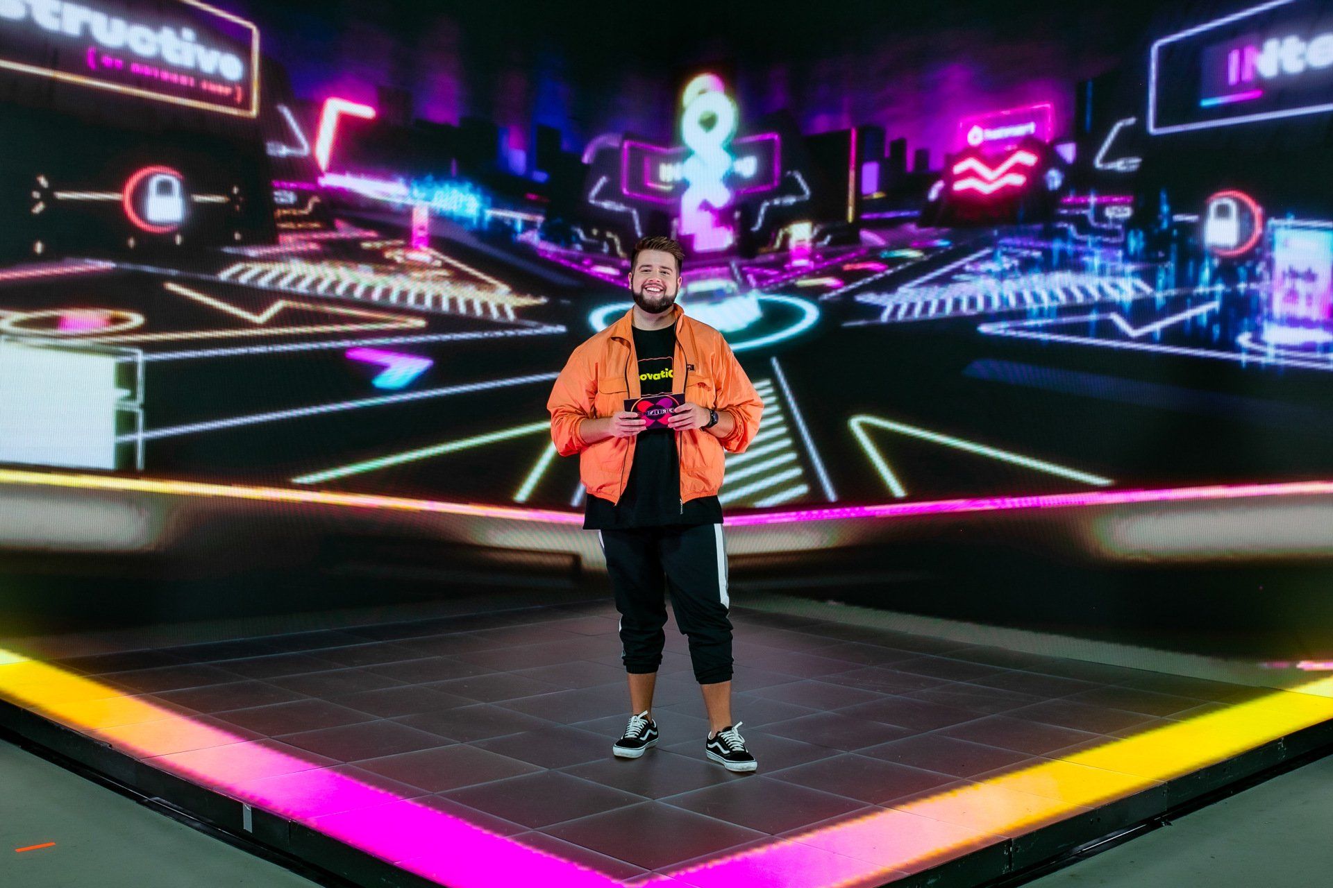A man is standing on a stage in front of a large screen.
