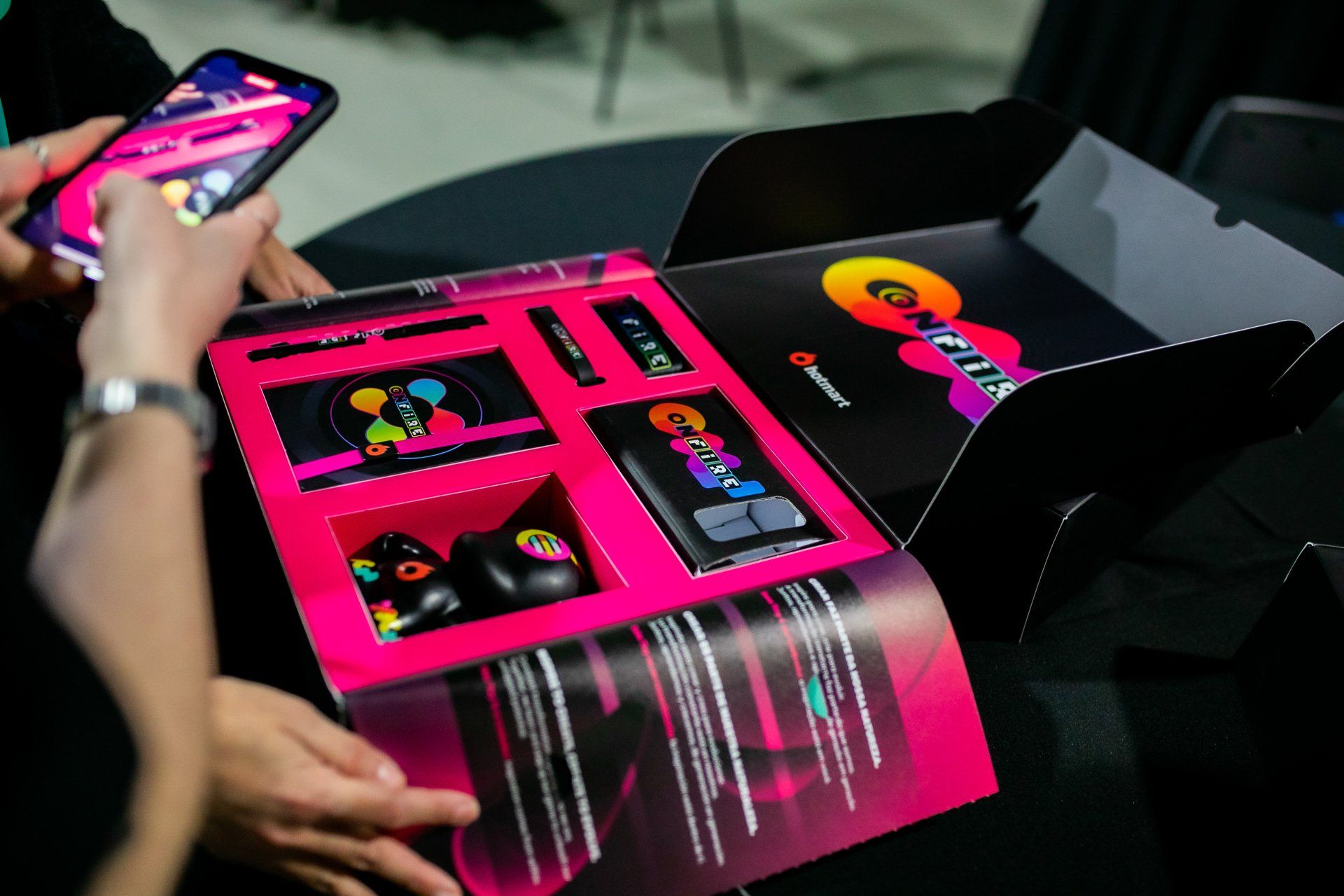 A person is holding a cell phone next to a pink box
