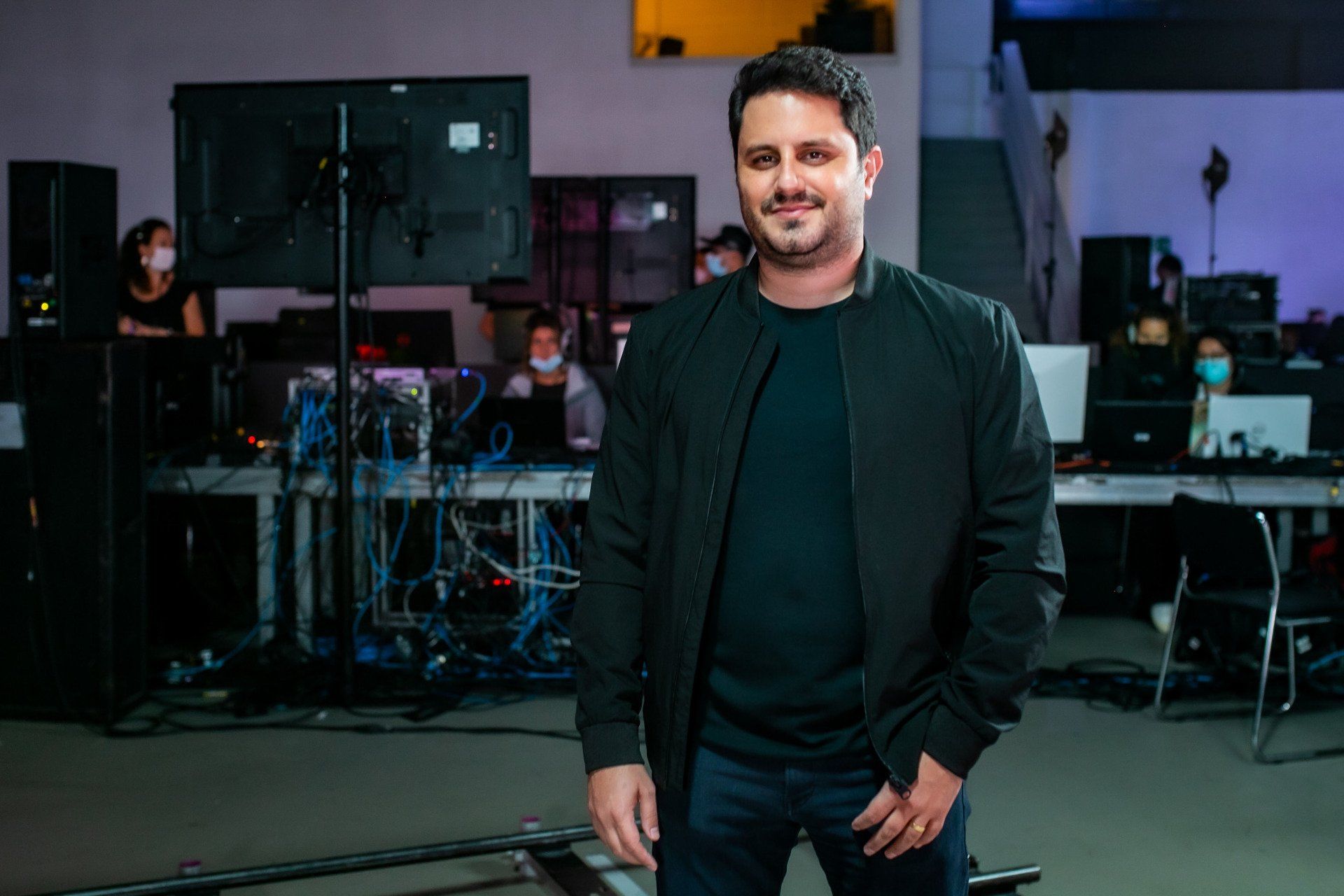 A man in a black jacket is standing in a room.