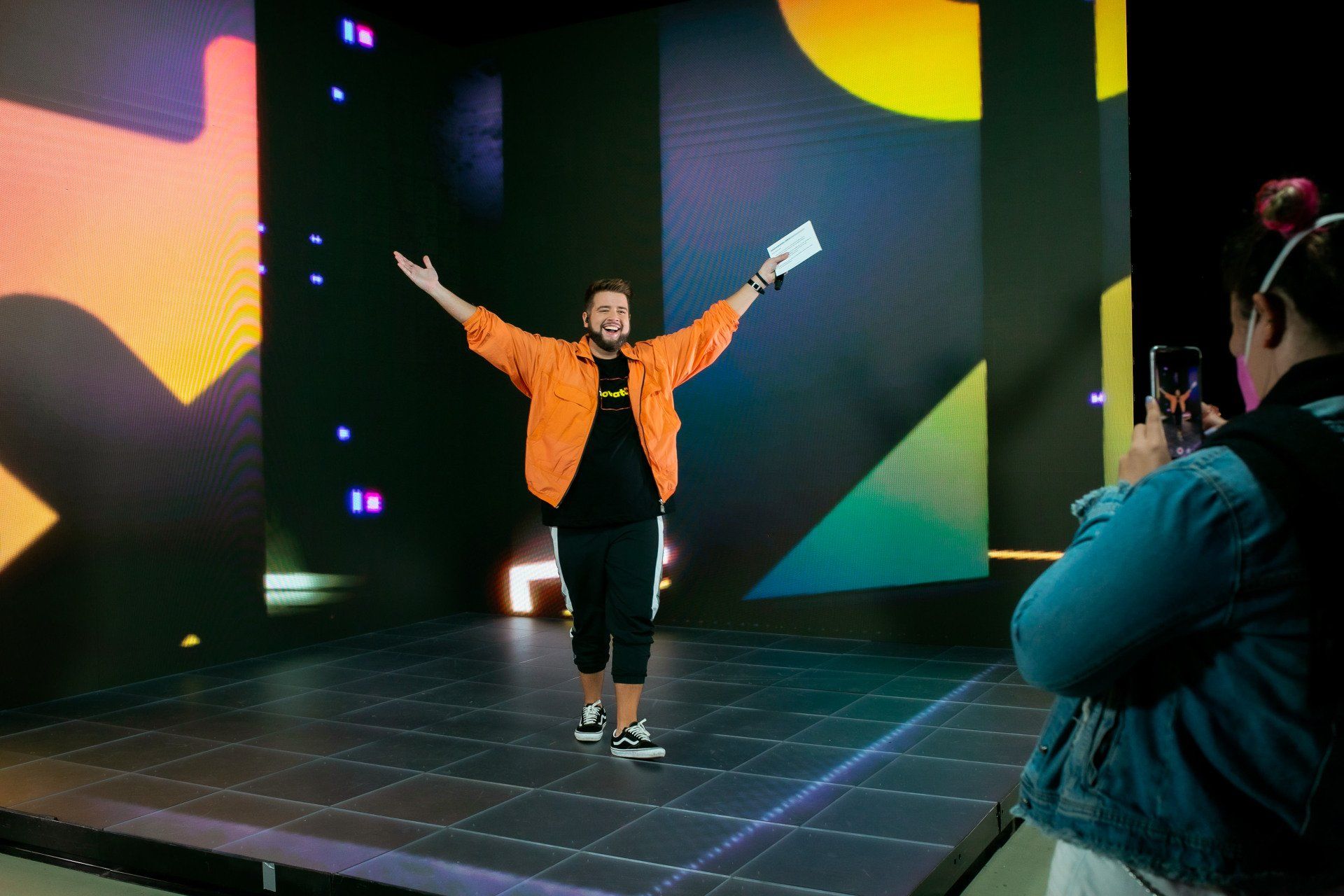 A woman is taking a picture of a man on a stage.