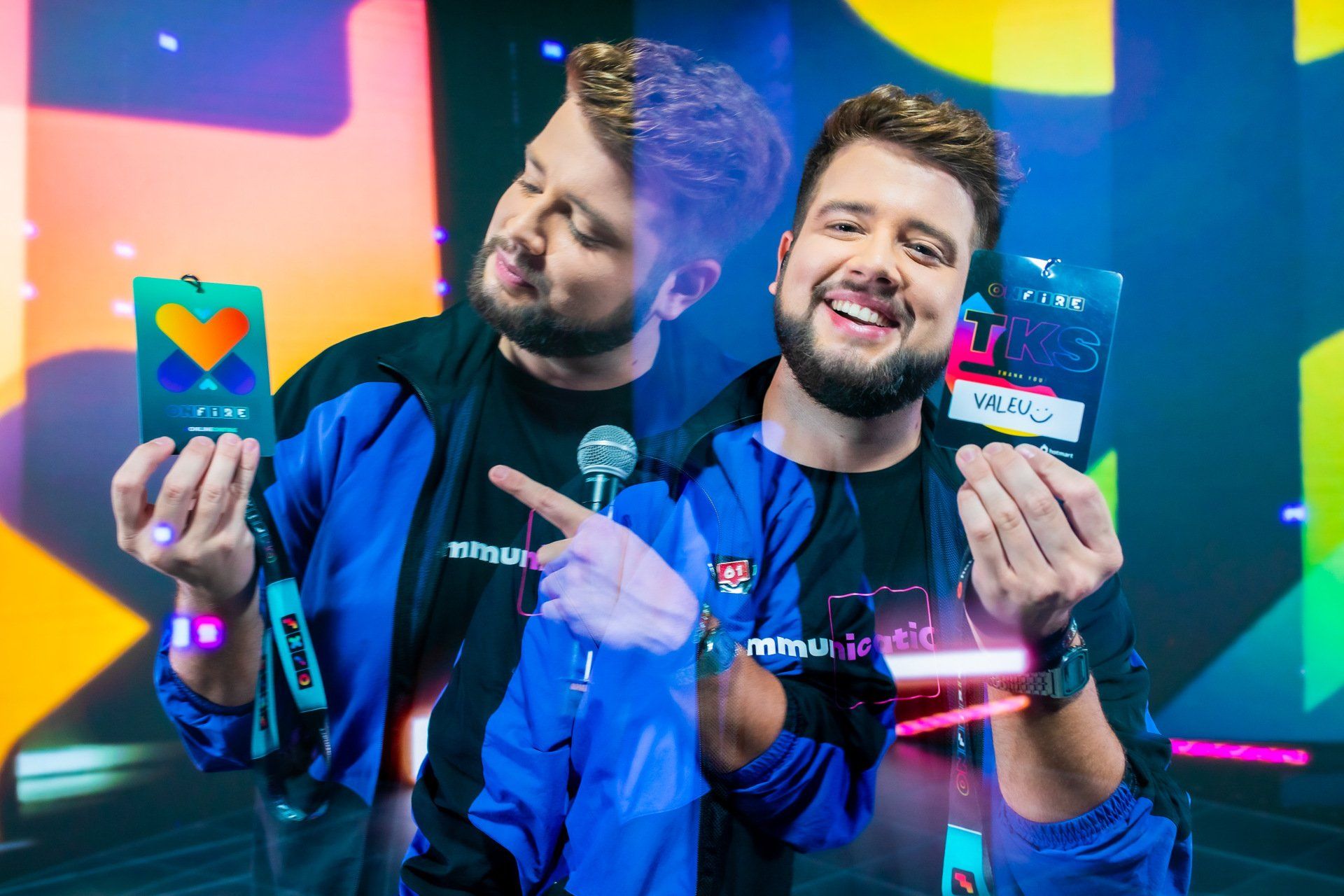 Two men are standing next to each other holding a microphone and a card.