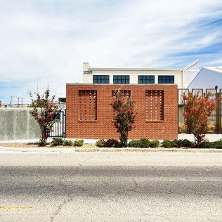 A brick building with a fence around it is sitting next to a road.