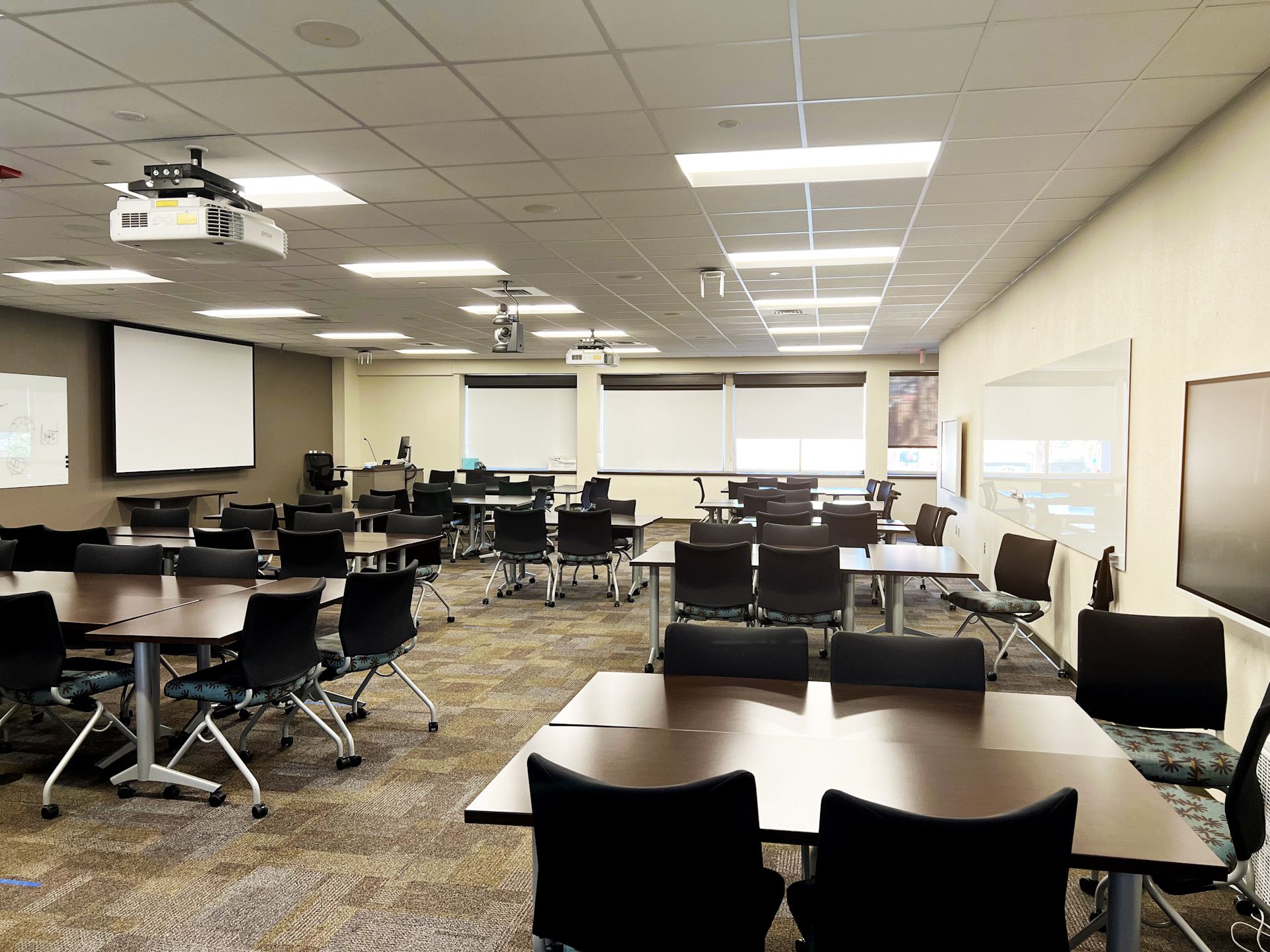 A large conference room with tables and chairs and a projector.