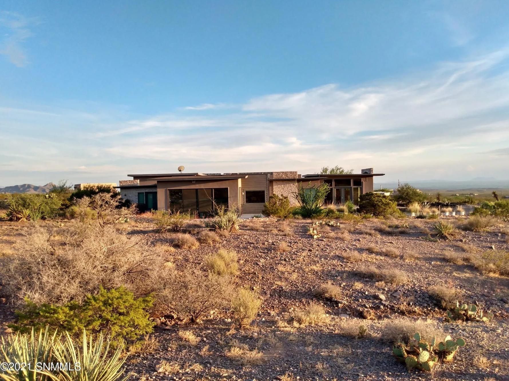 A large house is sitting in the middle of a desert.