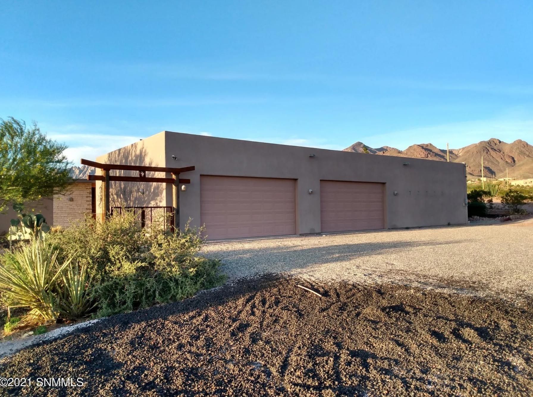 A large house with two garage doors and mountains in the background