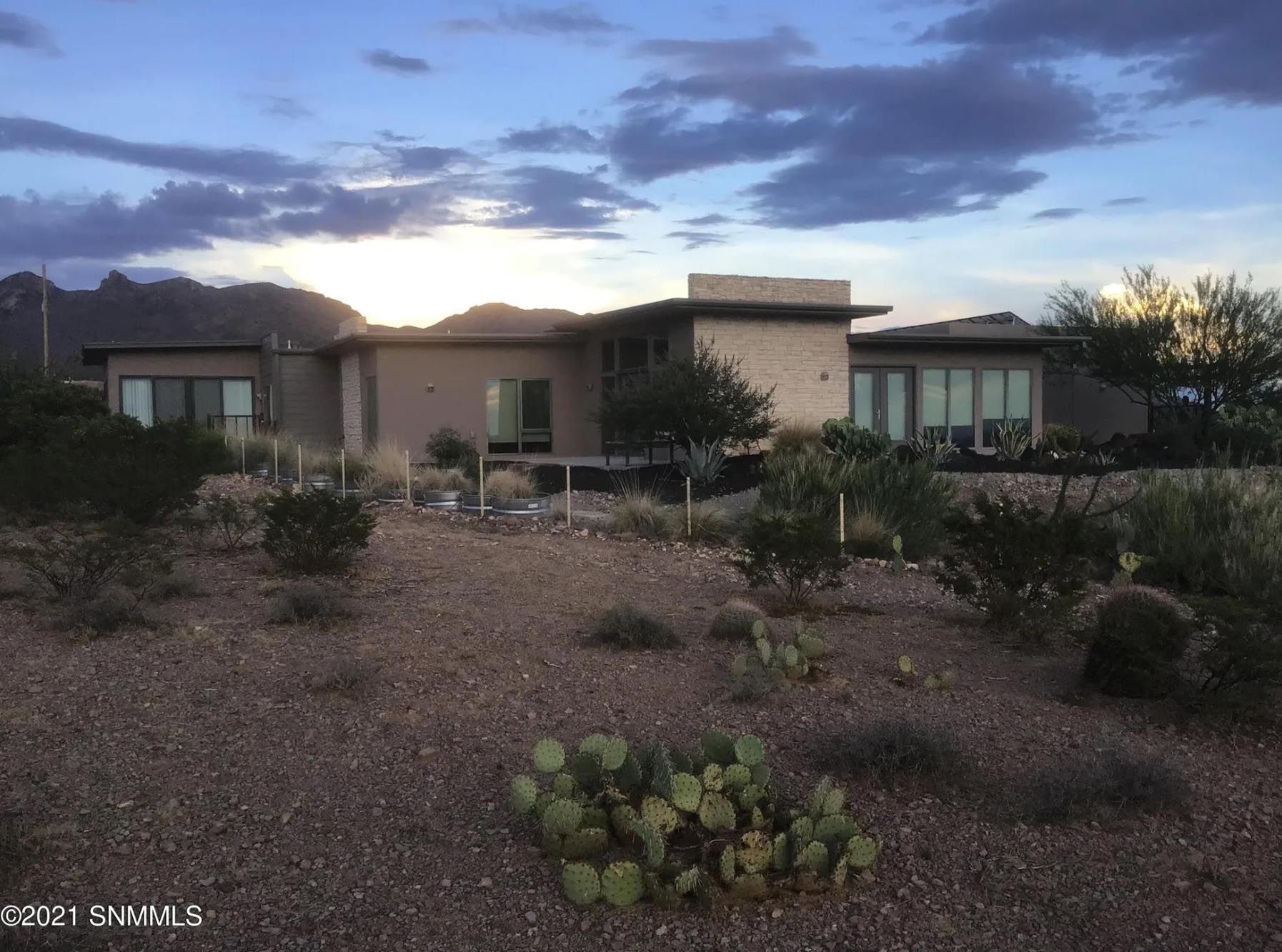 A large house in the desert with a cactus in front of it