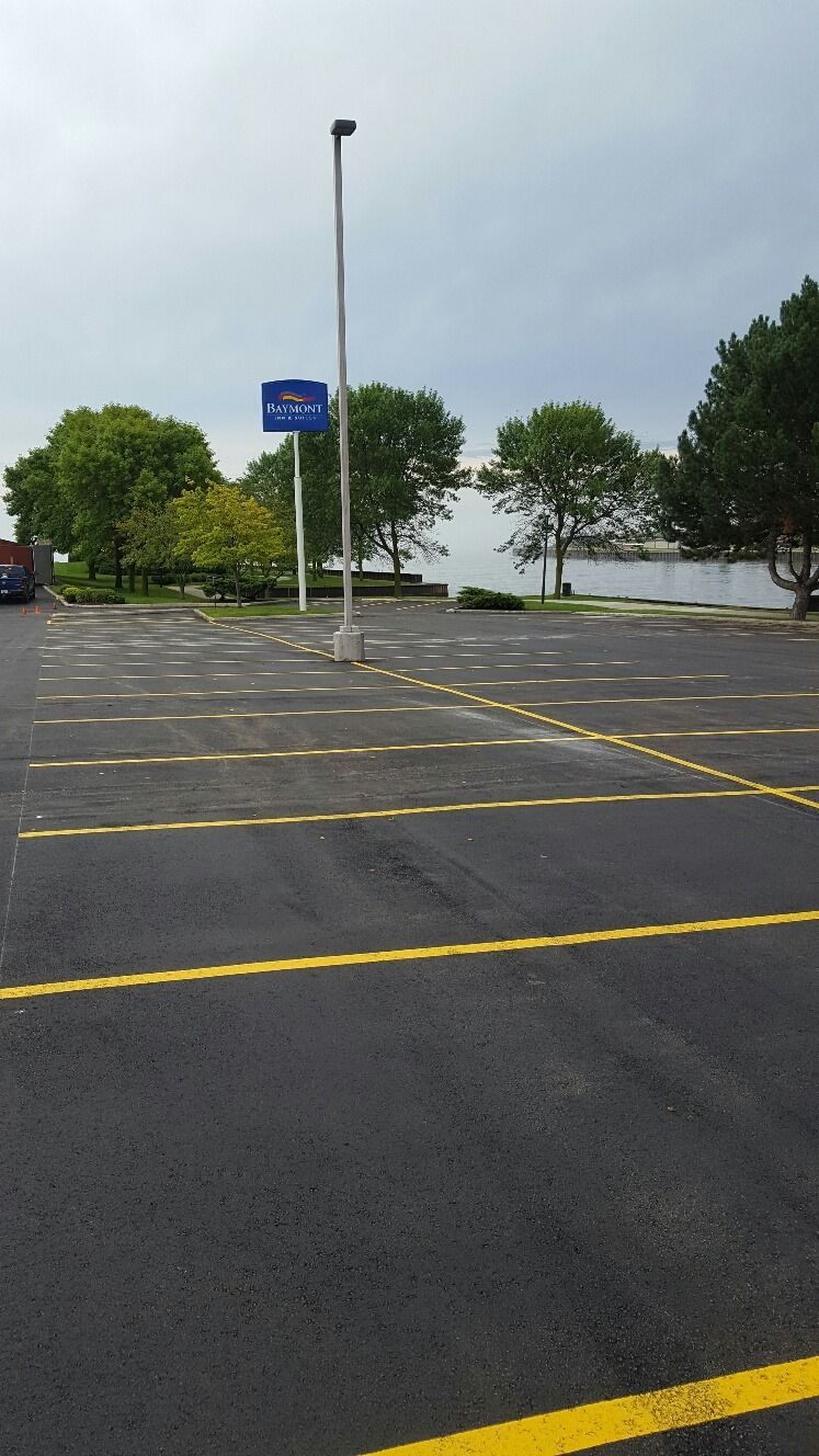 A parking lot with yellow lines and trees in the background