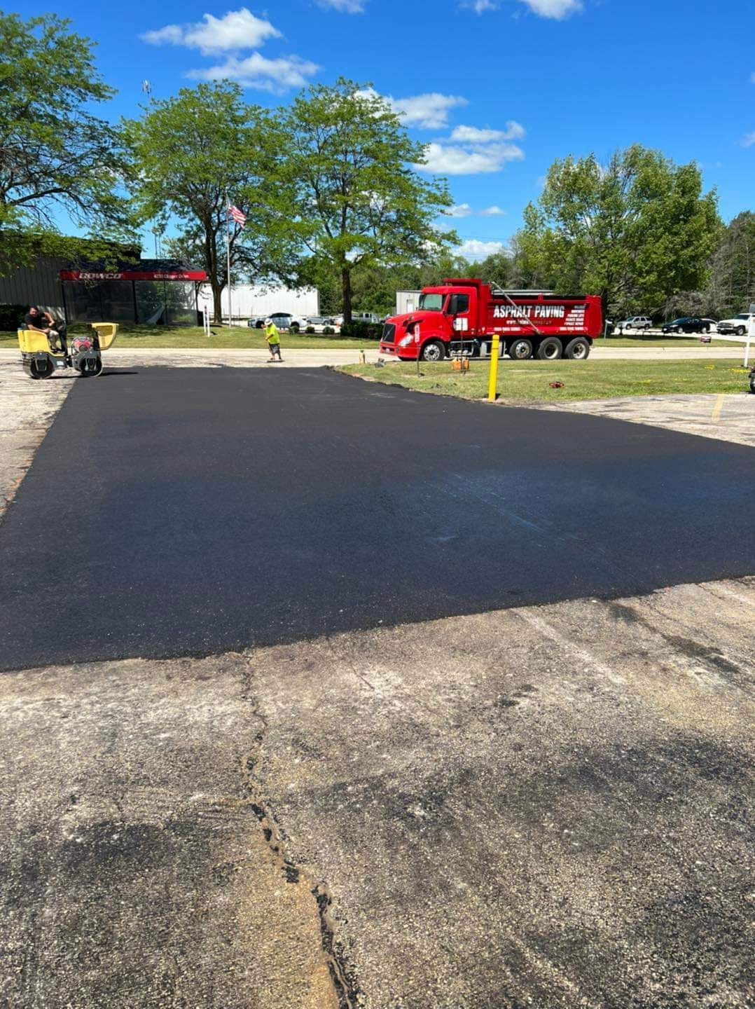A red truck is parked in the middle of a paved driveway.
