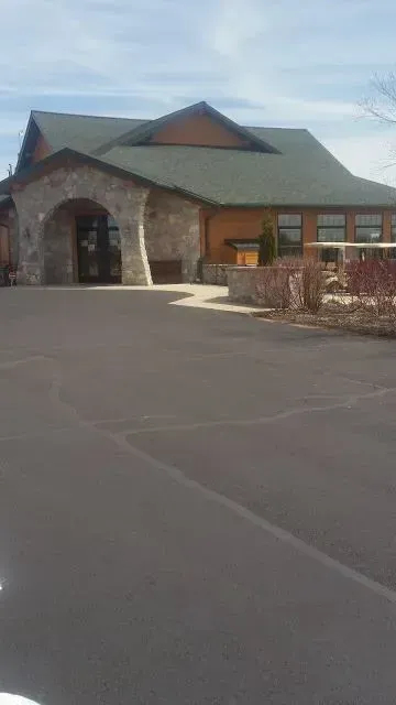 A large house with a green roof and a parking lot in front of it.