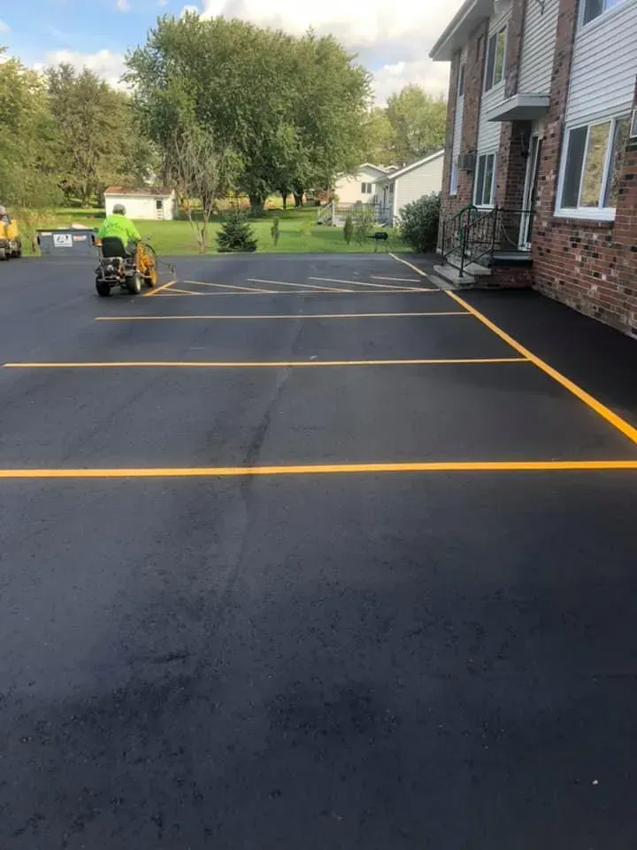 A man is riding a lawn mower in a parking lot.