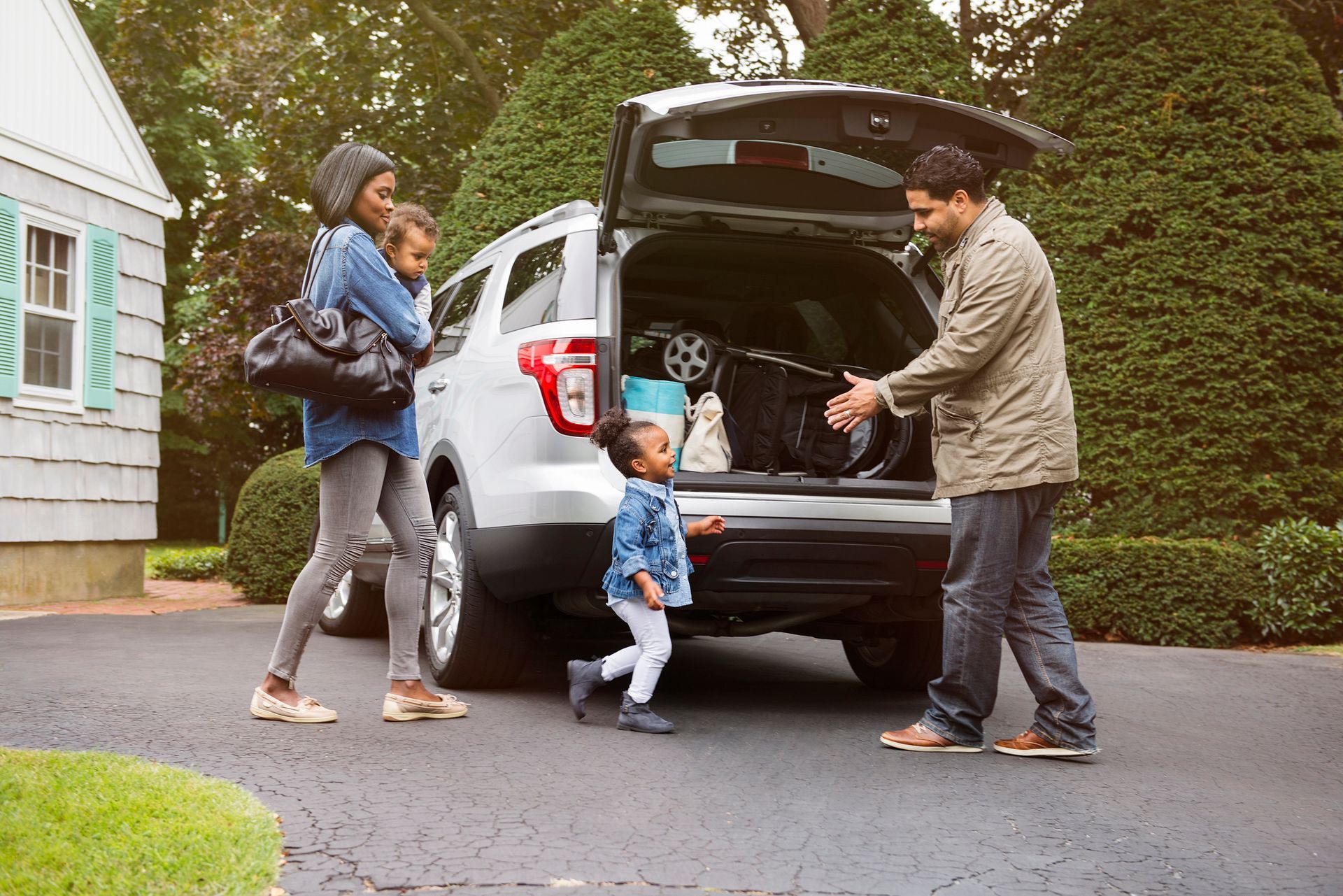 A family is putting their luggage in the back of a car.