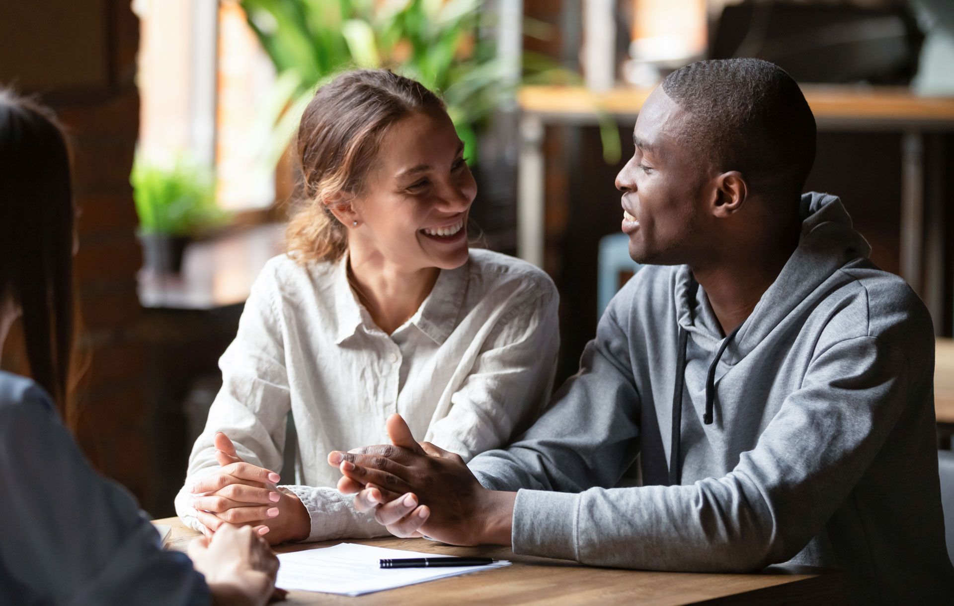 A man and a woman are sitting at a table talking to each other.