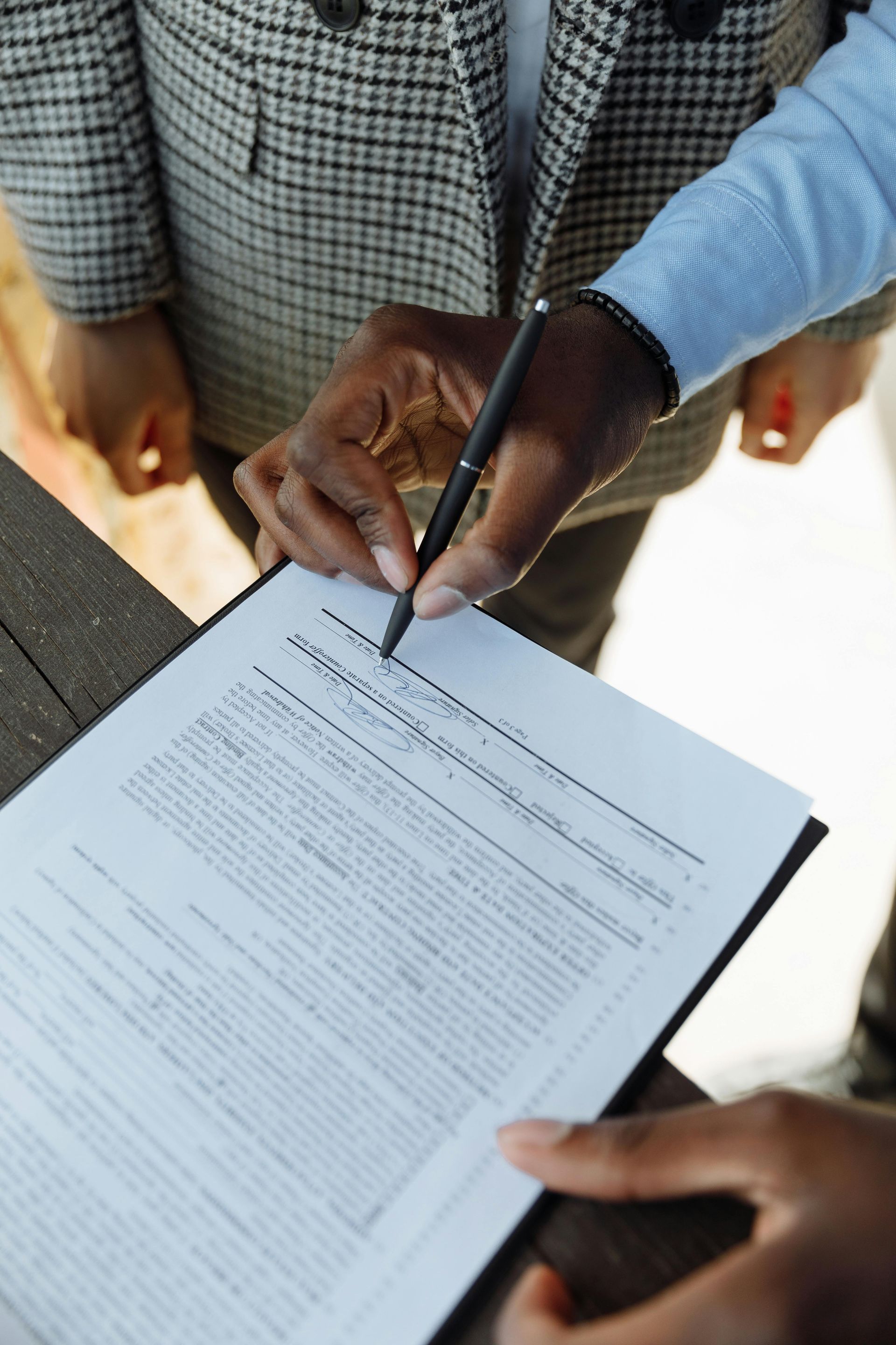 A person is signing a document with a pen.