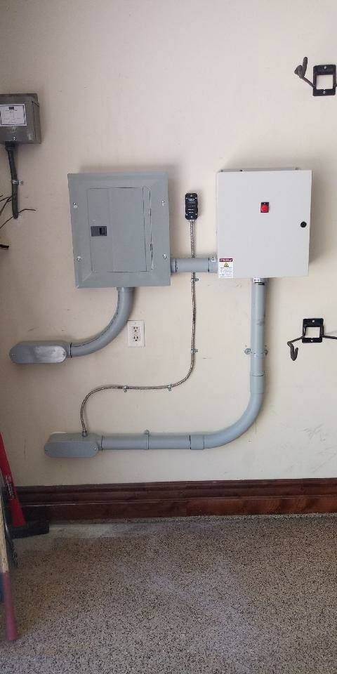 Electrical boxes and conduit on a wall. Gray and white boxes connected by gray conduit.