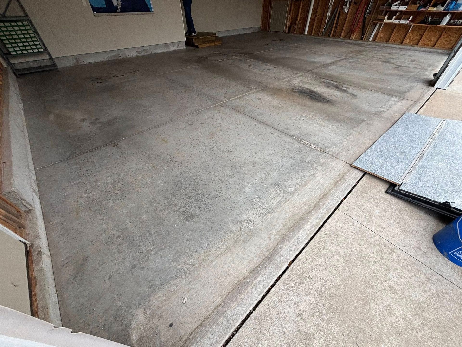 Concrete garage floor with dark stains. A person stands near the back.