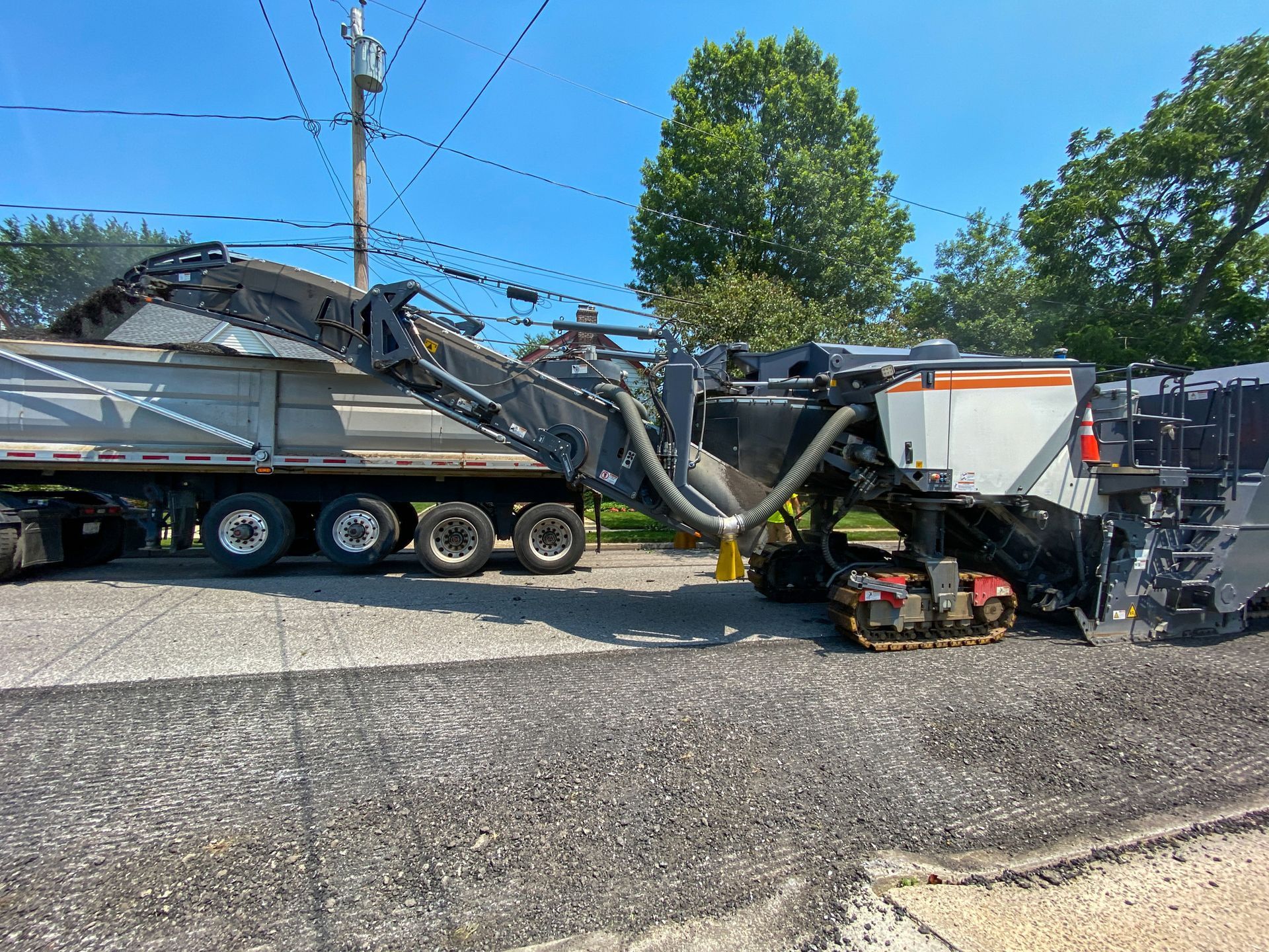 A large machine is sitting next to a dump truck.
