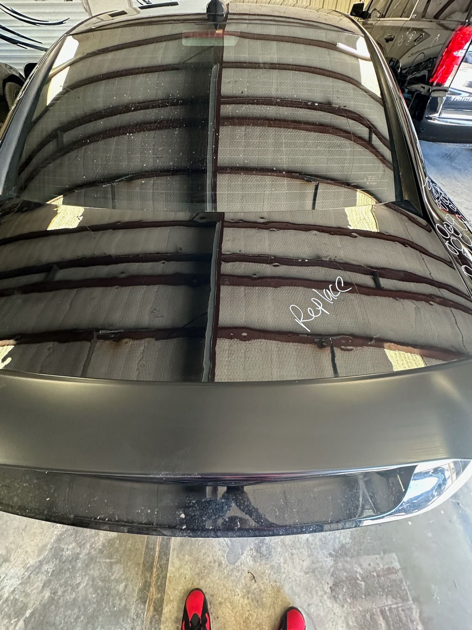 Glossy black car hood with reflections inside a garage, viewed from above