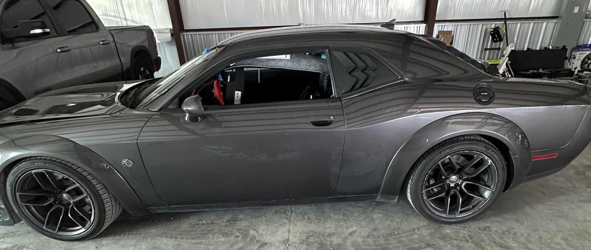 Gray sports car parked indoors with black rims and side profile visible