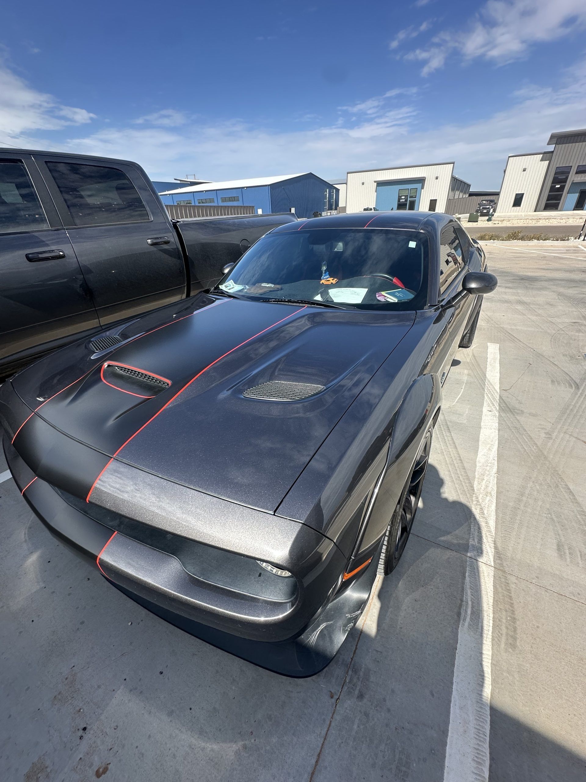Black sports car with red pinstripes parked in a lot on a sunny day