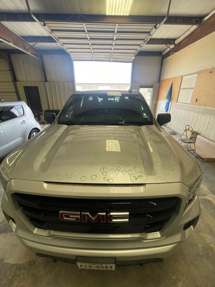 Silver GMC pickup parked inside a garage with the door open, front view.