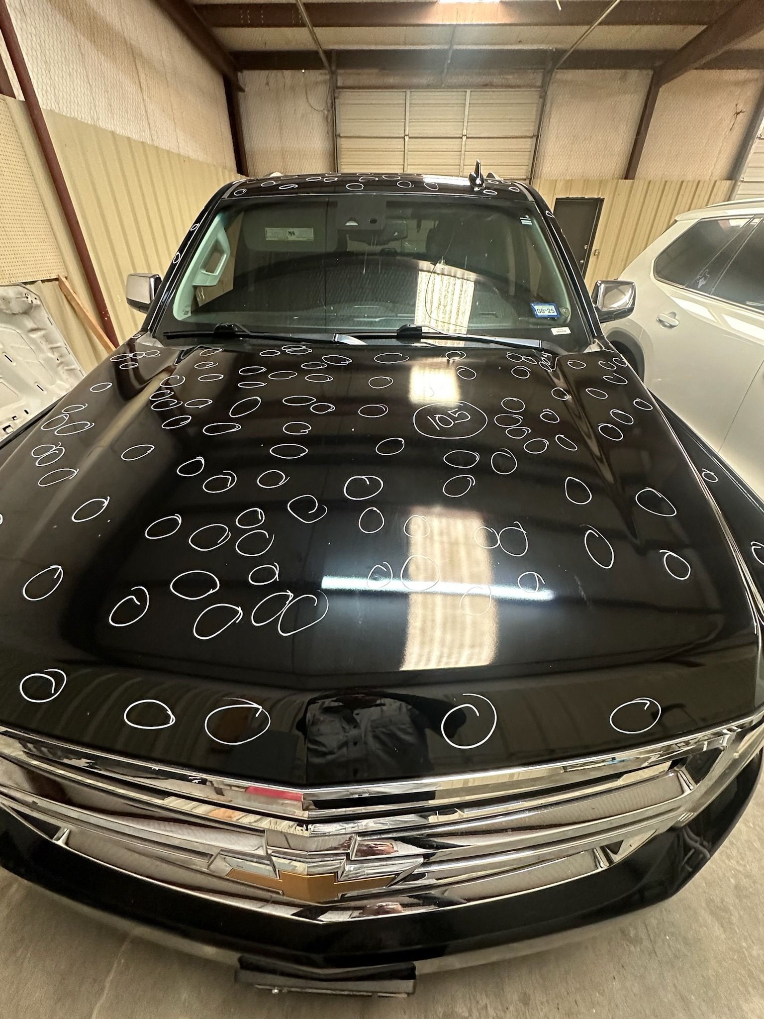 Black SUV parked indoors under bright lights, front view in a garage or showroom