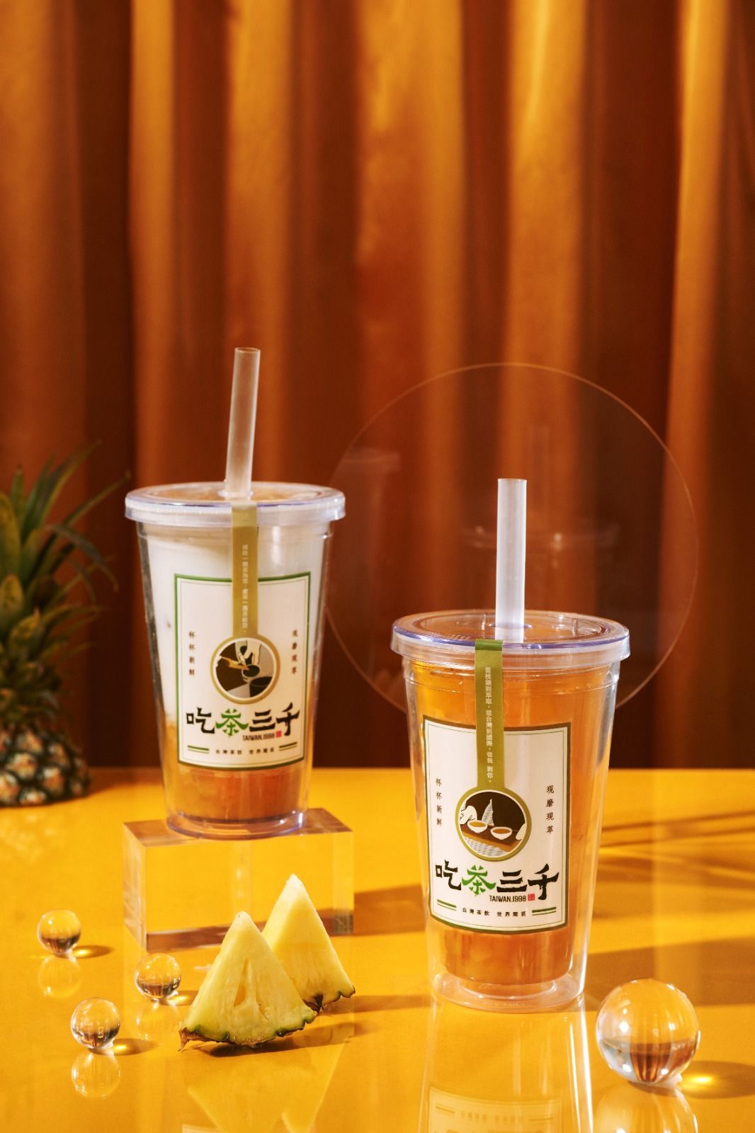 Two plastic cups of iced tea with lemon wedges on a yellow table against a warm brown backdrop