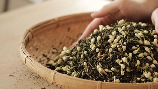 Hand sifting a basket of mixed seeds and grains on a tabletop