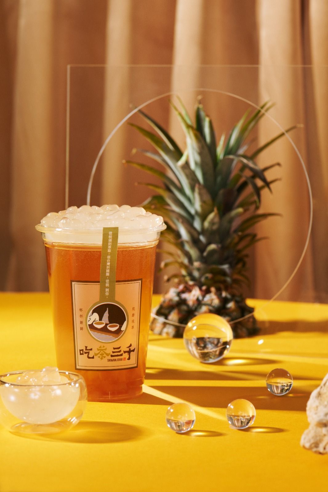 Iced beer in a glass on a yellow table with pineapple and small crystals in a warm, golden setting