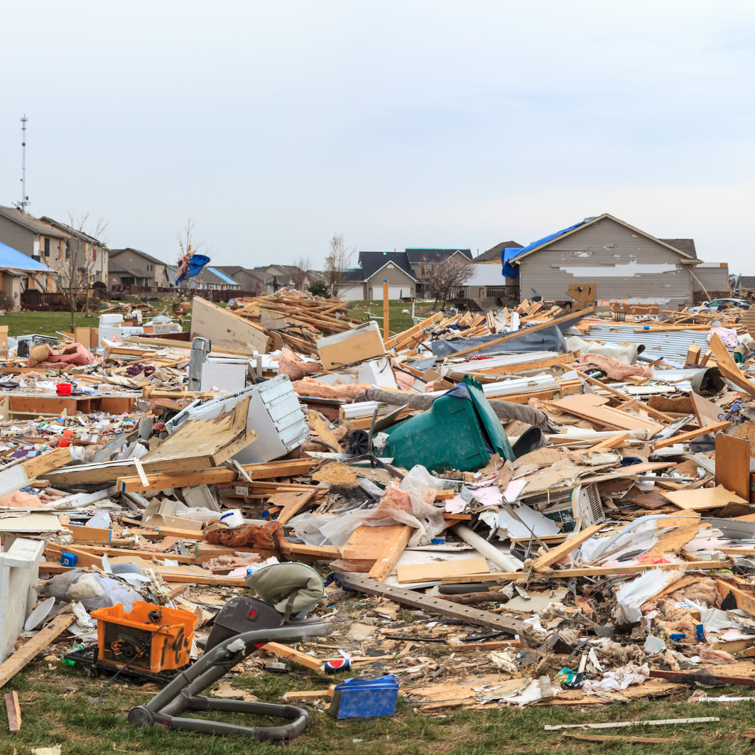 A pile of rubble in a field with houses in the background