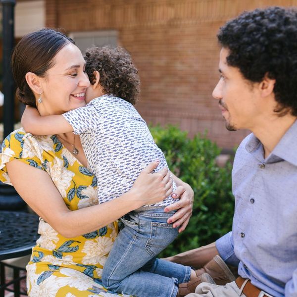 A woman is holding a child while a man looks on