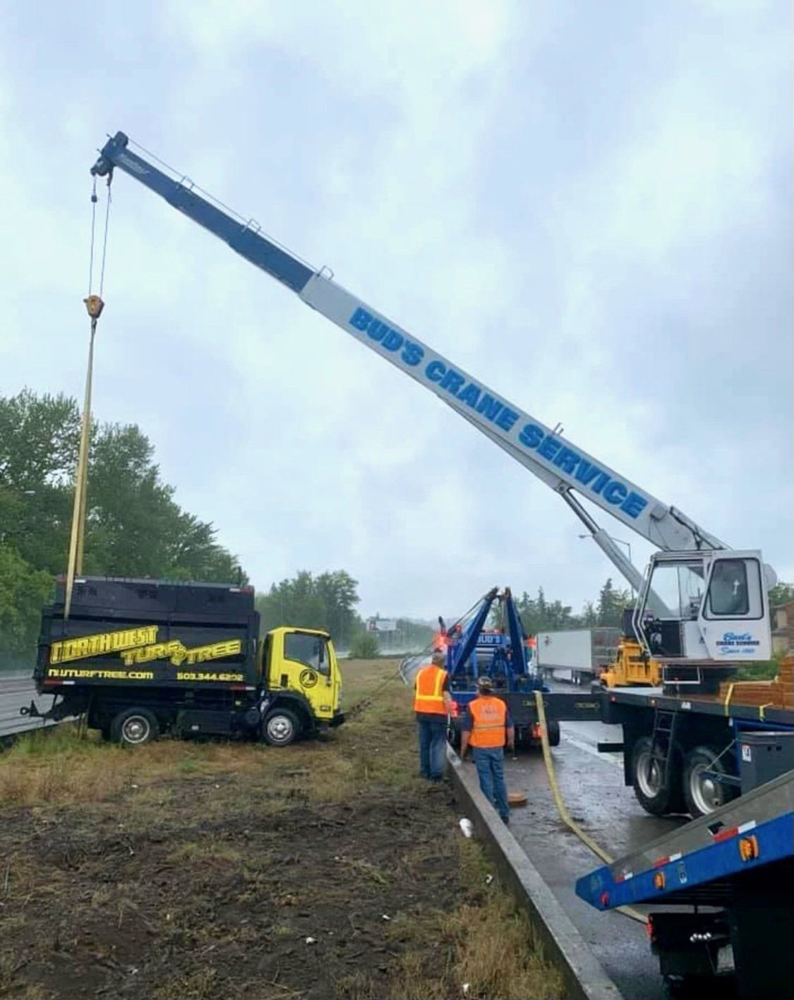 A crane lifting a large black truck — Oregon City, OR  — Bud's Crane Service Inc