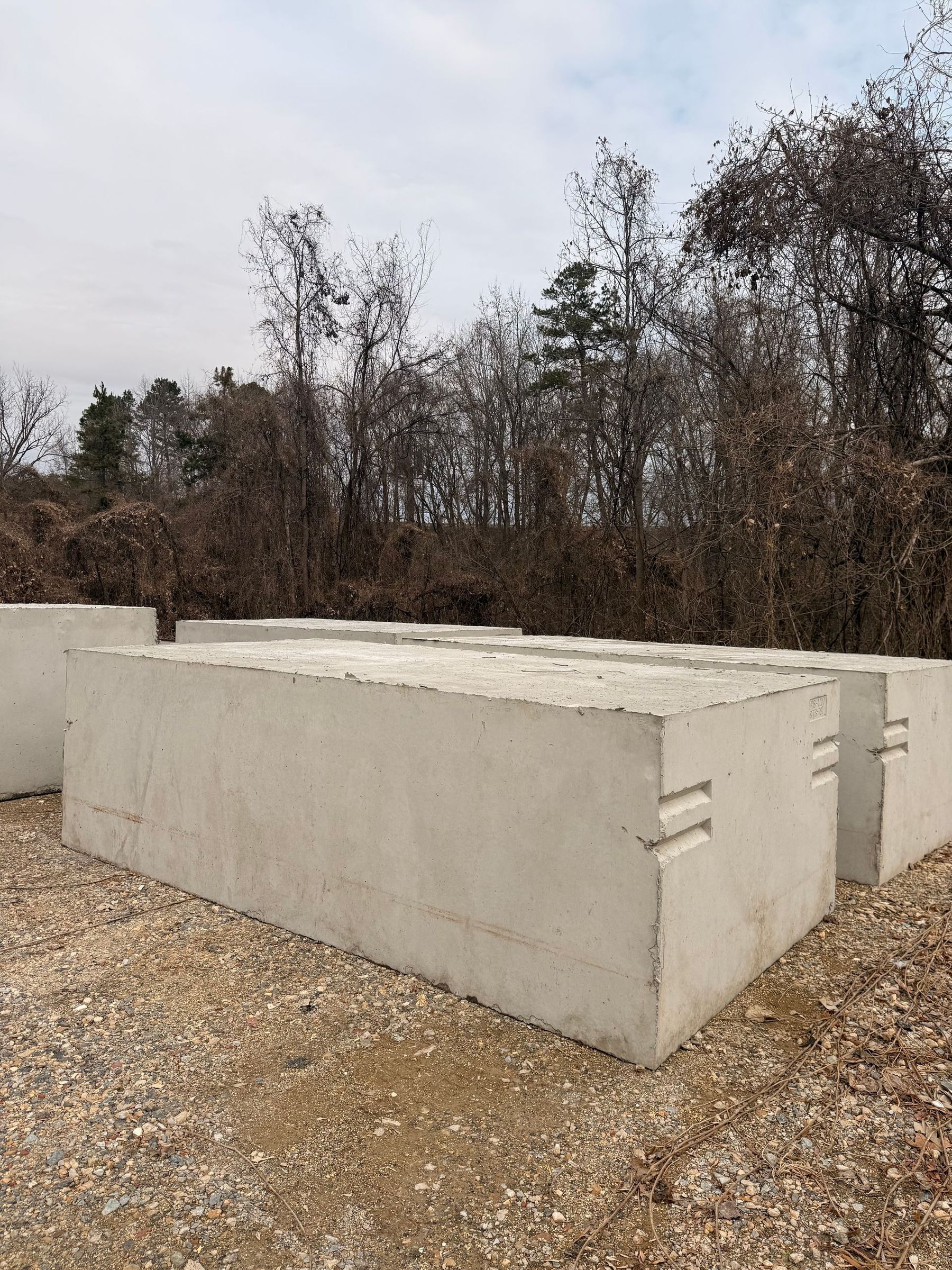 A rectangular concrete slab partially buried in grass, with loose dirt beside it.