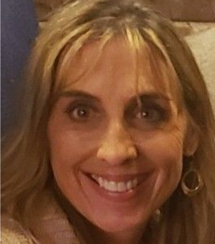 A smiling person with long blonde hair and hoop earrings, captured in a close-up portrait.