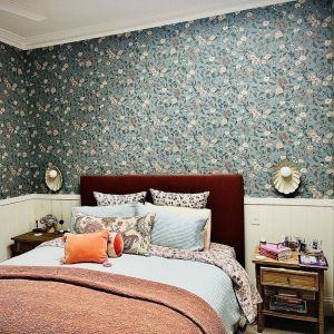 A bedroom with a bed , nightstand , and floral wallpaper.