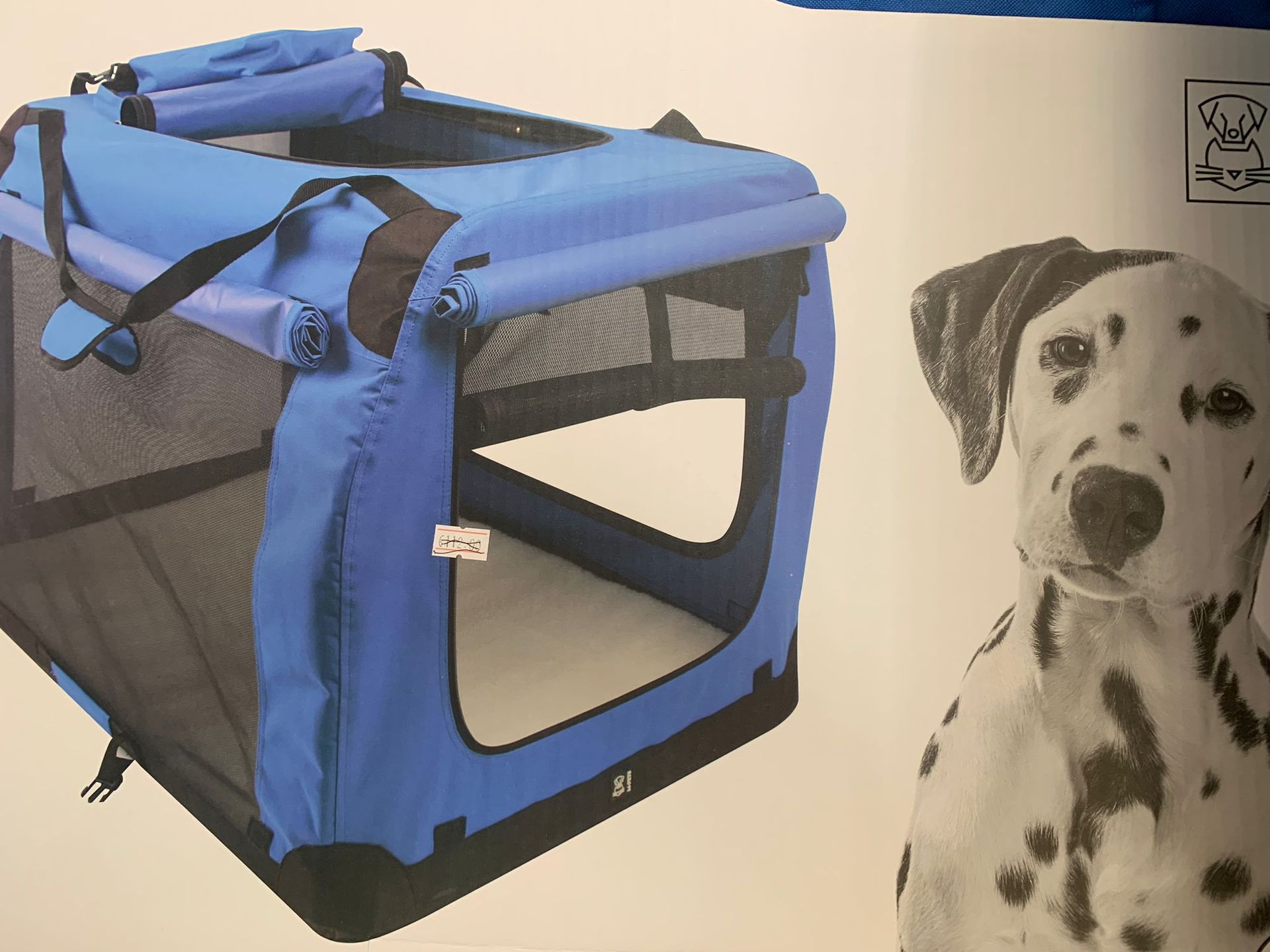 Un cane dalmata è seduto accanto a una gabbia per cani blu