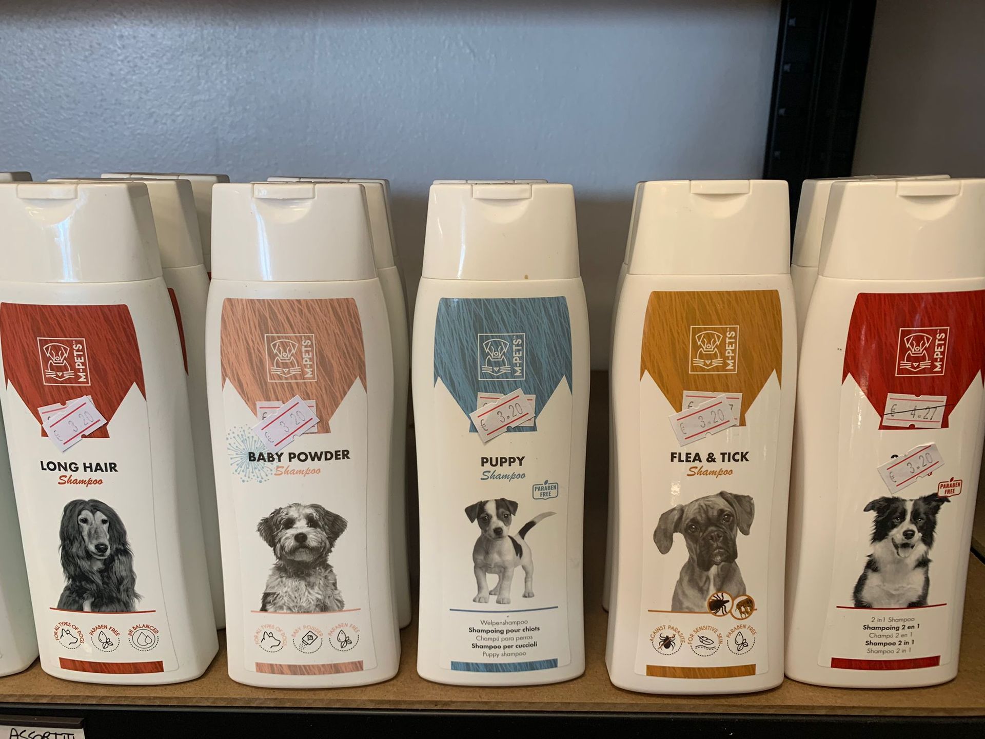 Una fila di bottiglie di shampoo per cani sono allineate su uno scaffale.