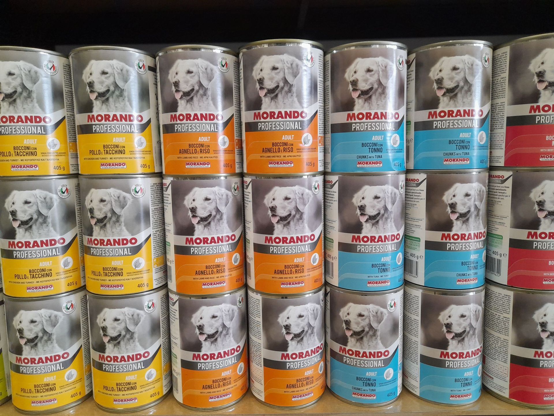 Un mucchio di lattine di cibo per cani sono impilate una sopra l'altra su uno scaffale.
