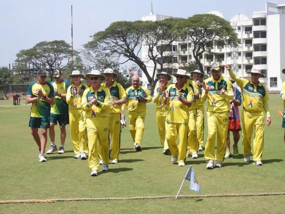 An Australian cricket team in yellow uniforms, walking on the field
