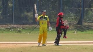 Cricket players on a field, one holding a bat and raising a hand